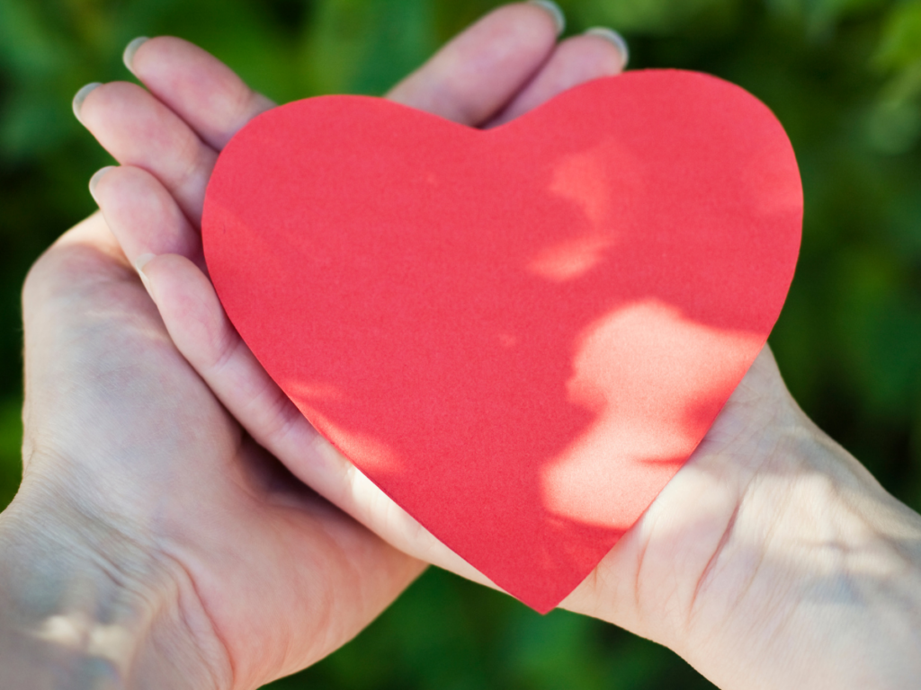 A heart held crossed hands on a green background