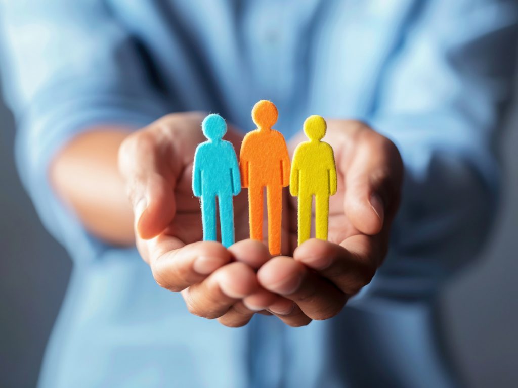 Close up of two hands cupped together holding a felt cutout of three people.