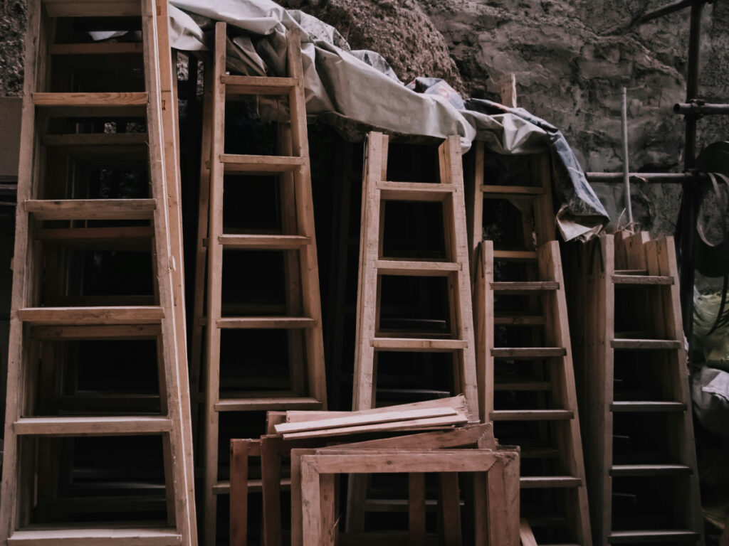 5 wooden ladders stacked against a stone wall, signifying the steps and ladders in a Classified salary range