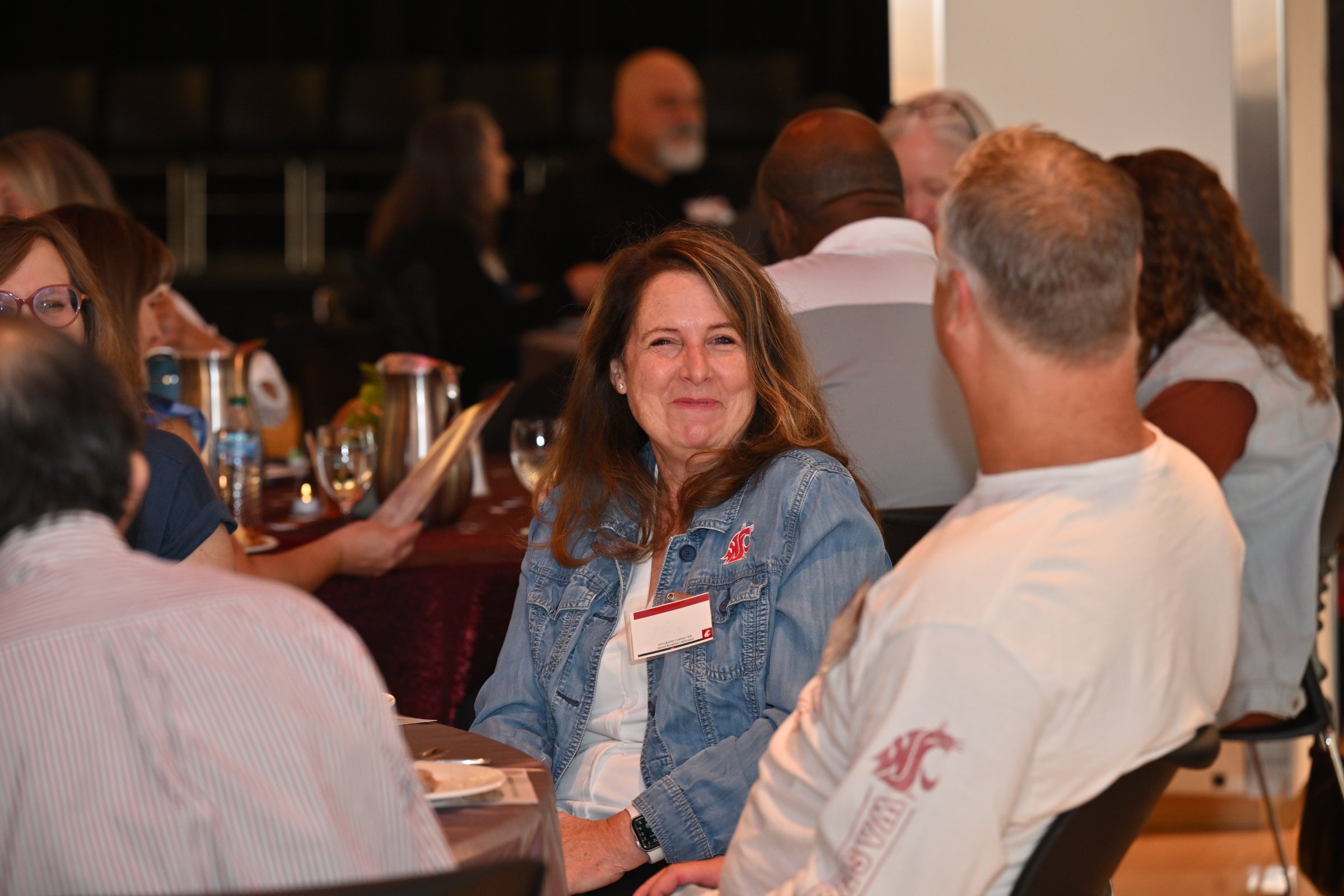 WSU employees at a table, with a woman looking at the camera and smiling.