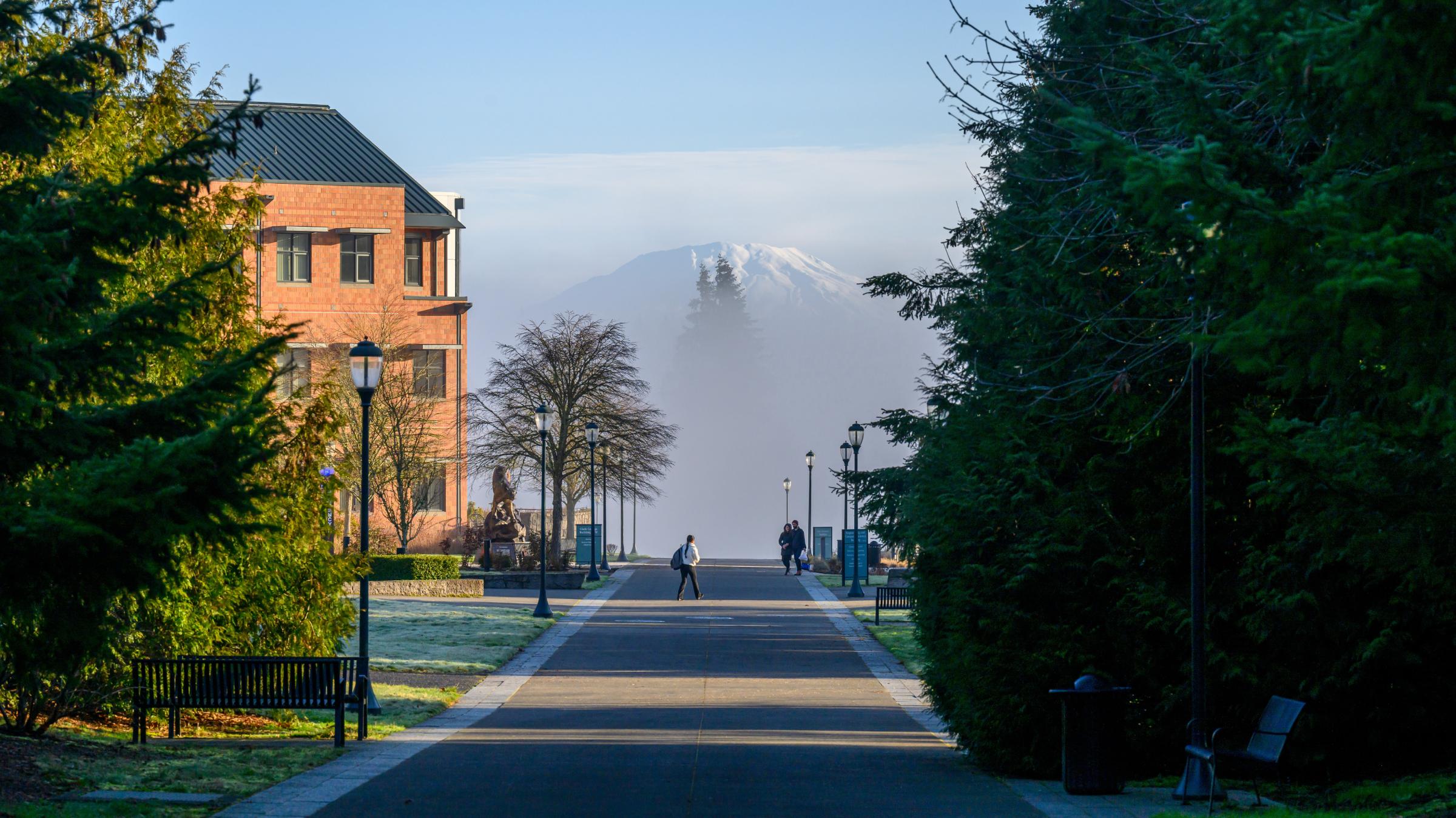 View of Vancouver campus in the Winter with trees in the foreground, the Clark College building to the left in the middle, and Mount St Helens shrouded in mist in the background.