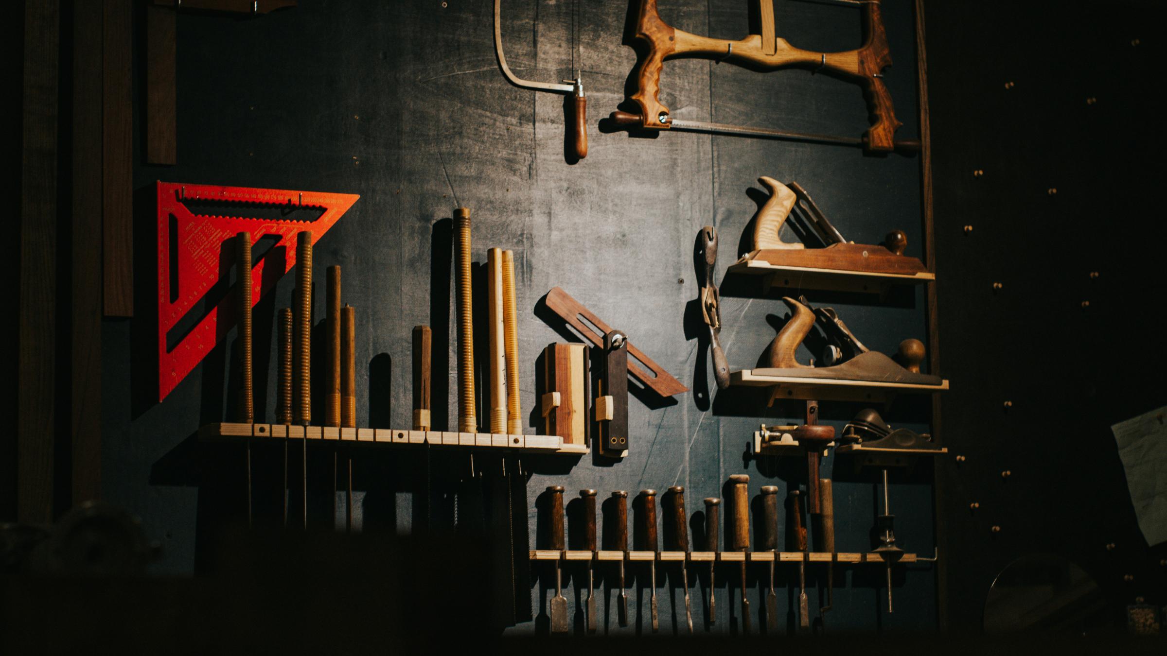 Neatly organized woodworking tools on a dark wall.