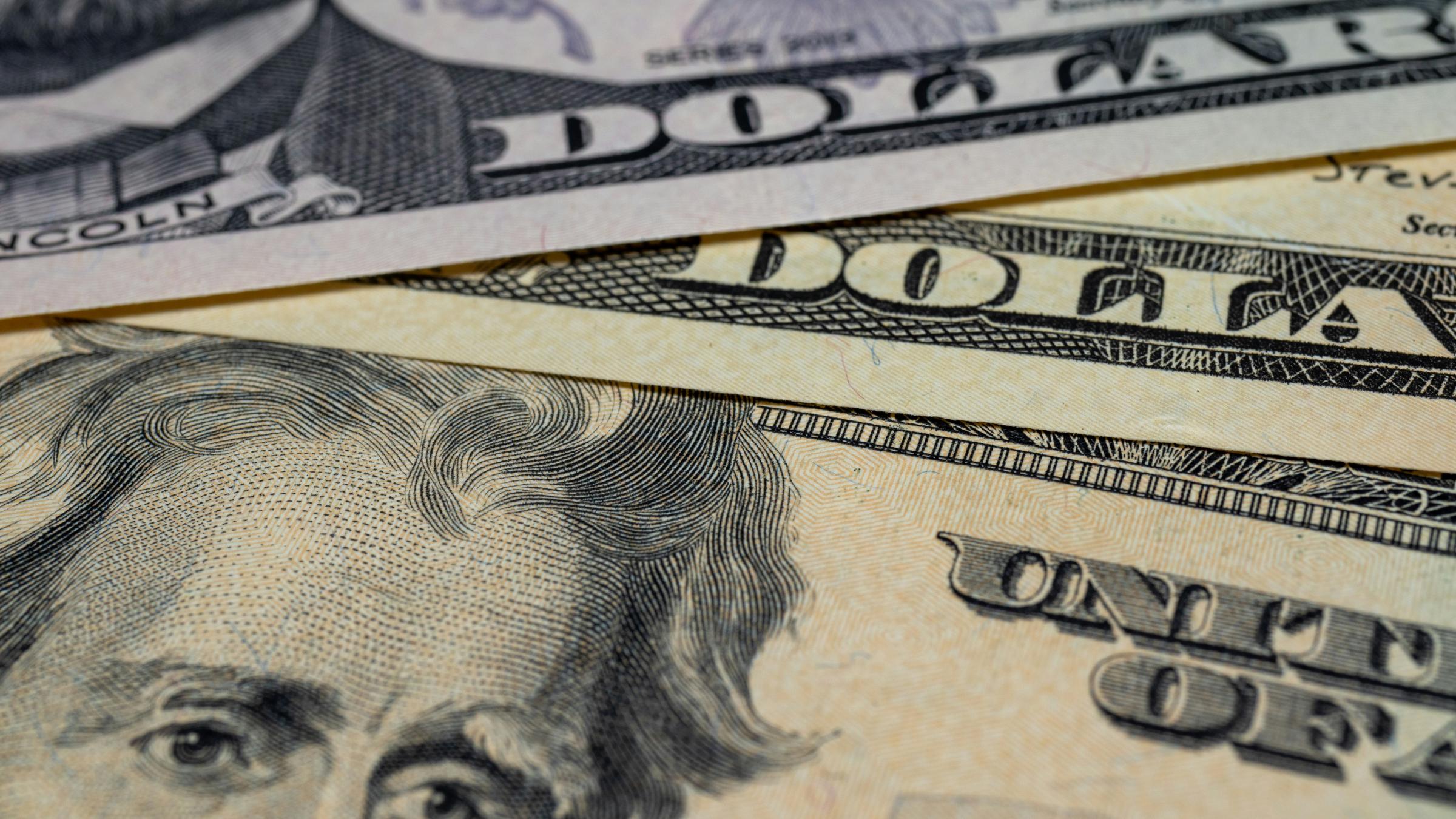 Close up view of a 20 dollar and 5 dollar bill focusing on the etchings of President Jackson and President Lincoln's faces.