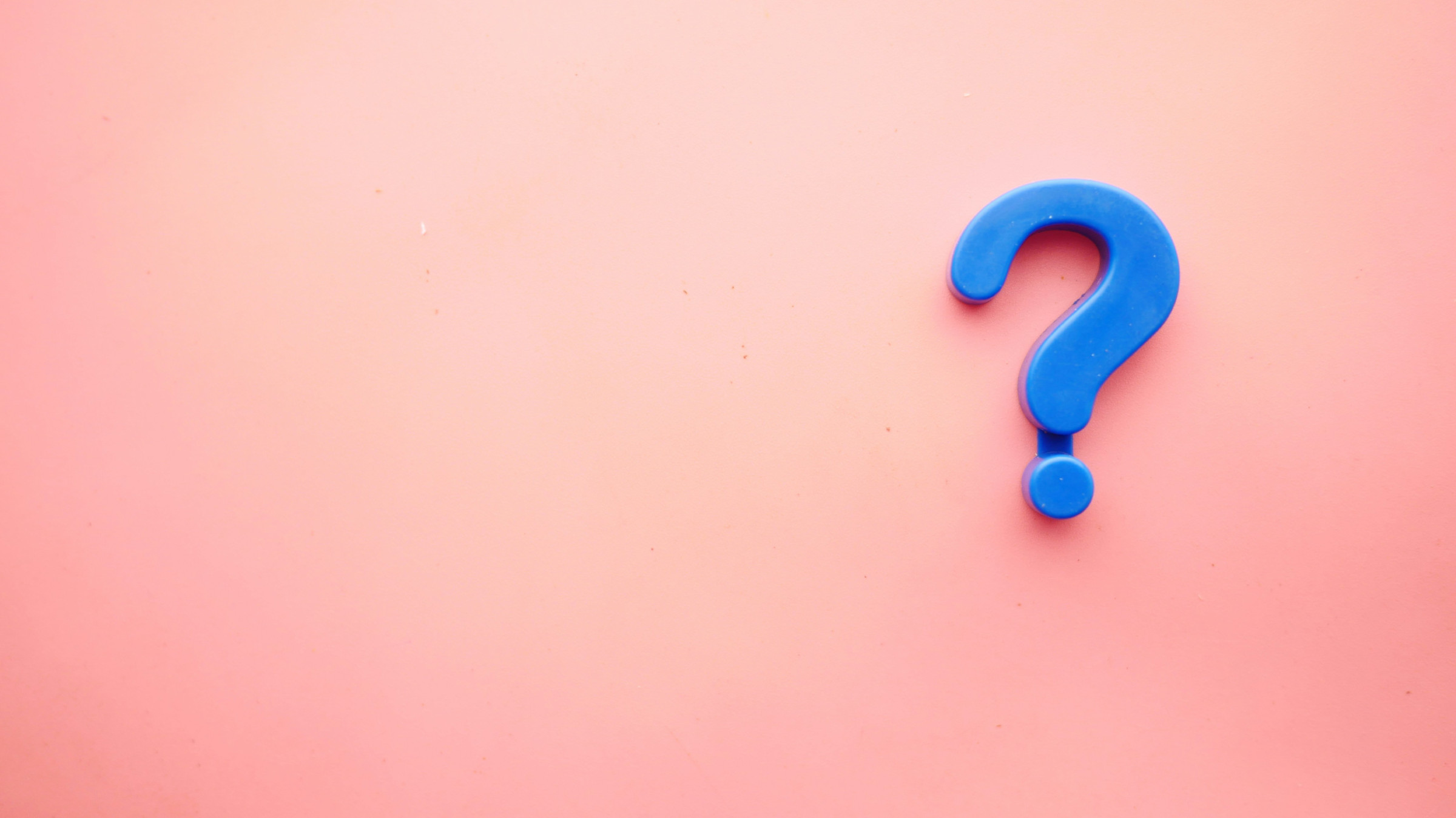 Blue plastic question mark on a pink background.