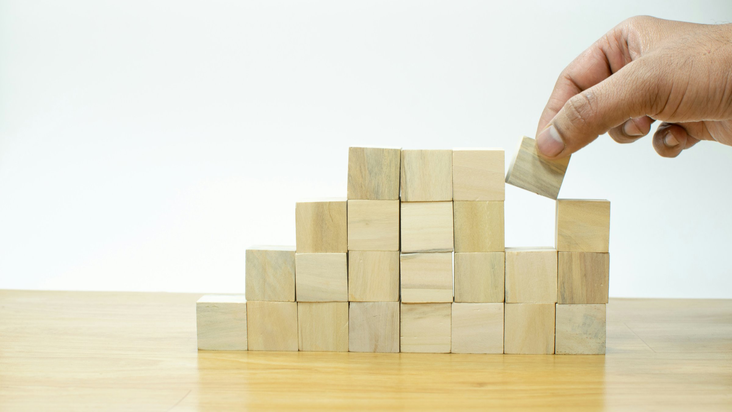 A partially built wall of square, wooden blocks, 8 blocks wide by 4 blocks high.