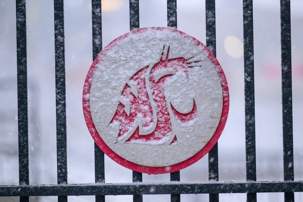WSU logo plaque on a black metal fence with snow on it.