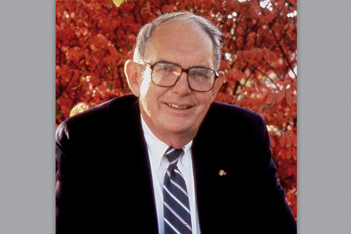 Dr. Gorham in a suit and tie with red autumn leaves filling the background.