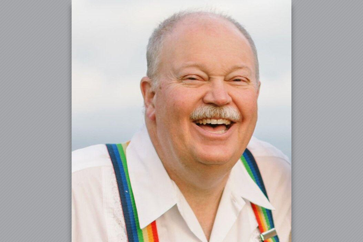 Thomas laughing. He's wearing a white dress shirt and rainbow suspenders.