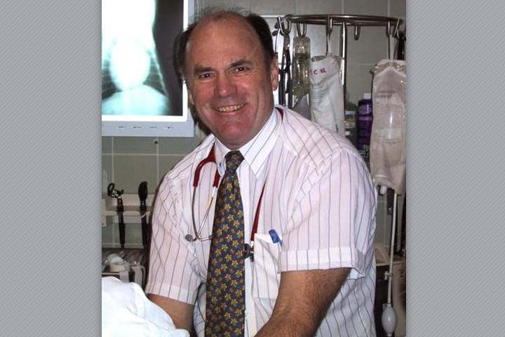 Dr. Haskins at his veterinary clinic. He is wearing a dress shirt and a tie.