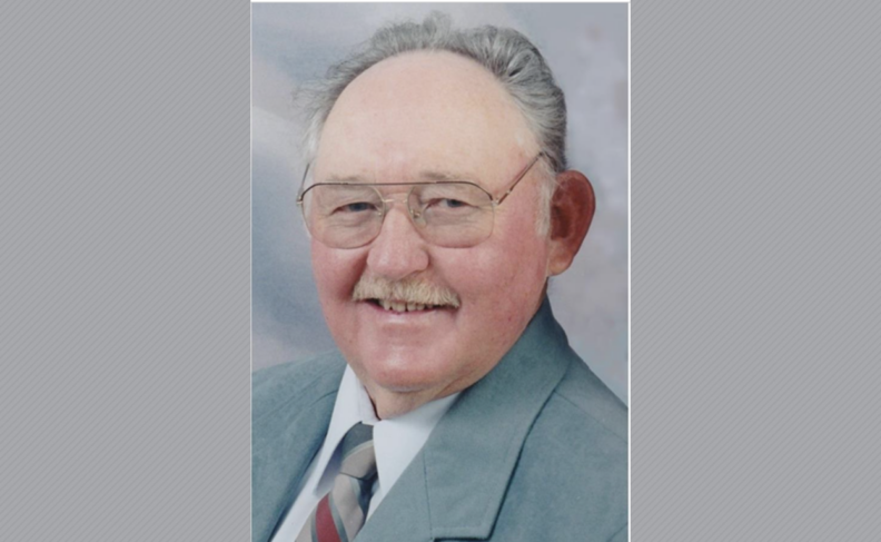 Headshot of William Brown wearing a blue suit and glasses.