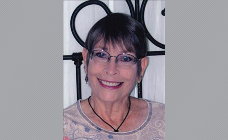 Peggy Harrer with short hair and wearing glasses.