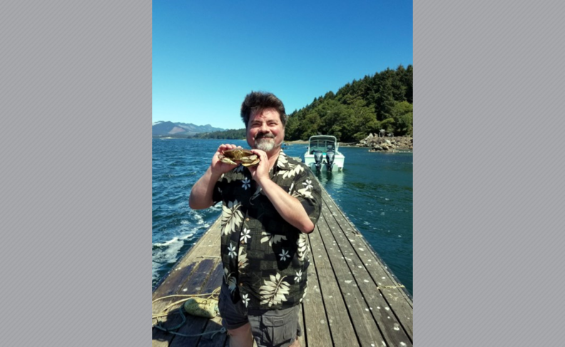 Mark Stanhope on a dock, holding a crab.