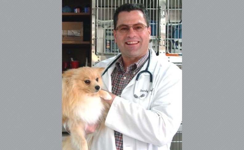 Photo of Randolf Webster in white coat, holding a dog.