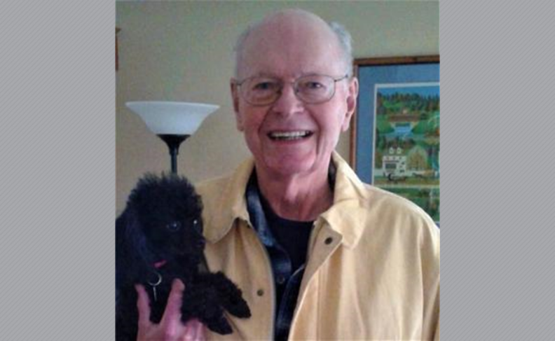 Photo of William Wellington holding small black dog.