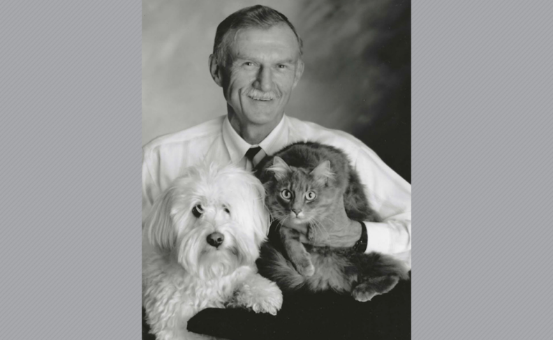 Black and white photo of Dr. Kubasch holding a white dog and a gray cat.
