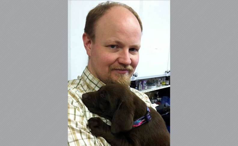 Photo of Dr. Luttinen in yellow plaid shirt holding a brown dog.