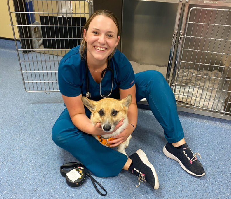 Student sits on floor holding dog
