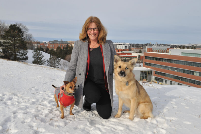 Dean Borjesson kneels in snow with two dogs