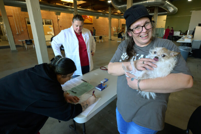 A client holds a small dog at the intake people for the Healthy Pets clinic. 