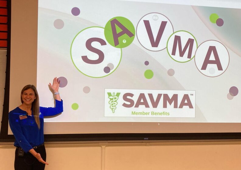 A guest speaker points to a powerpoint slide with information about SAVMA benefits.