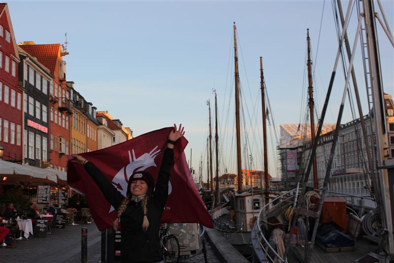 A student holding up a WSU Coug flag in Denmark