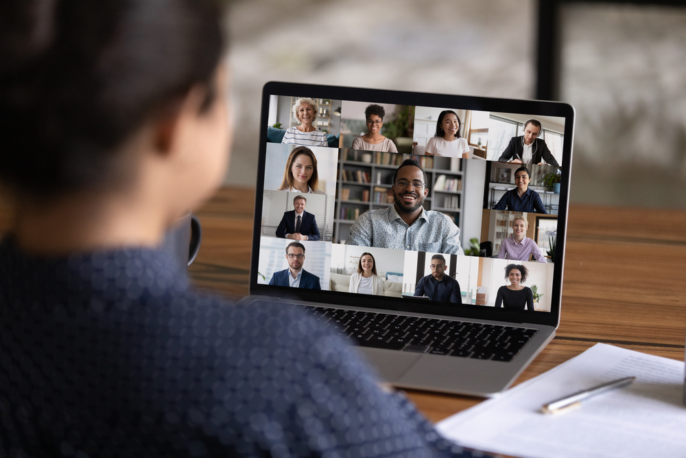 Over shoulder view of female individual on a digital virtual conference with several colleagues