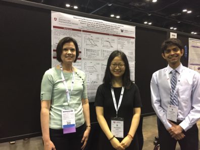 Three people smiling in front of a research poster