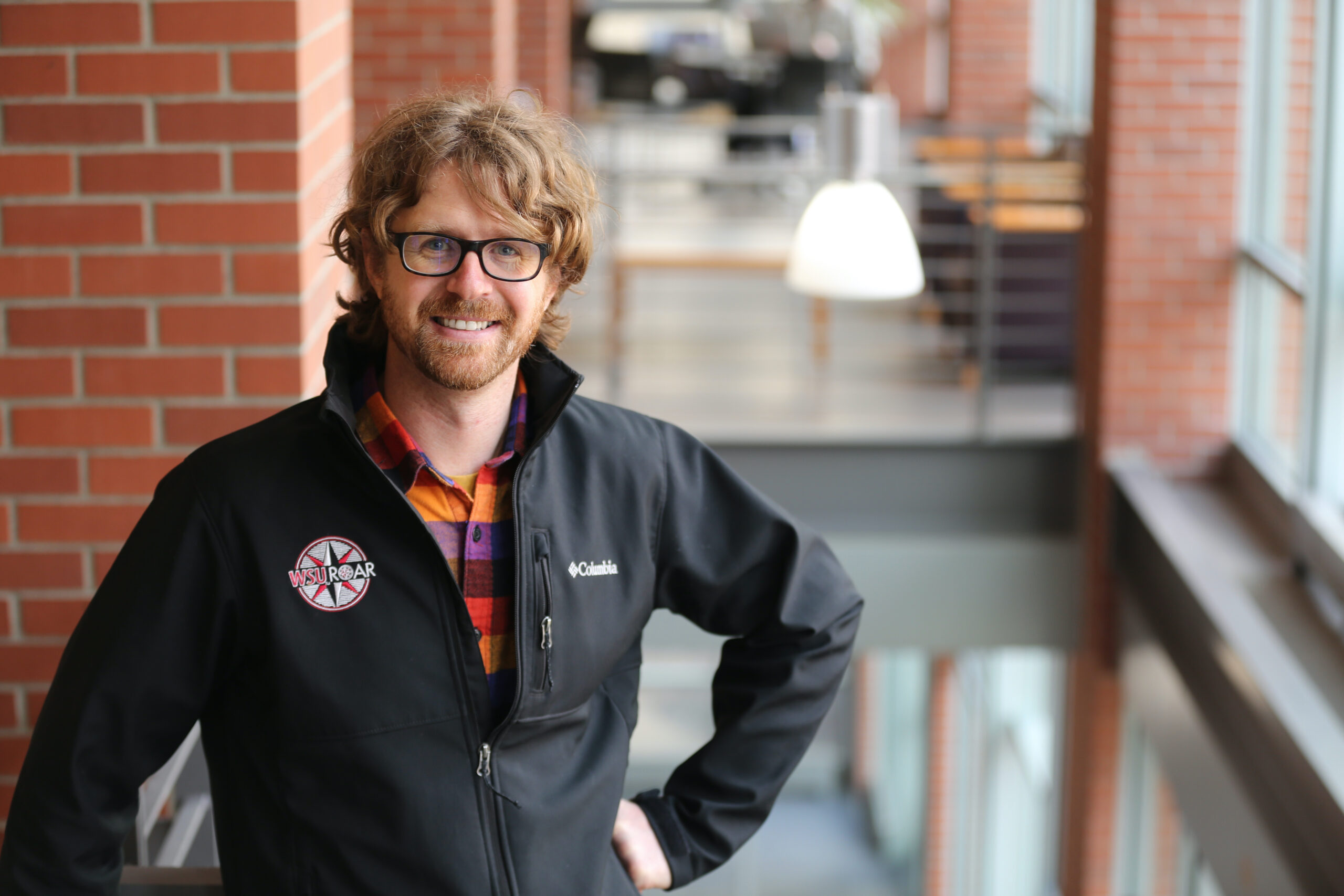 A portrait of Marcus Poppen standing inside a brick building on a staircase.