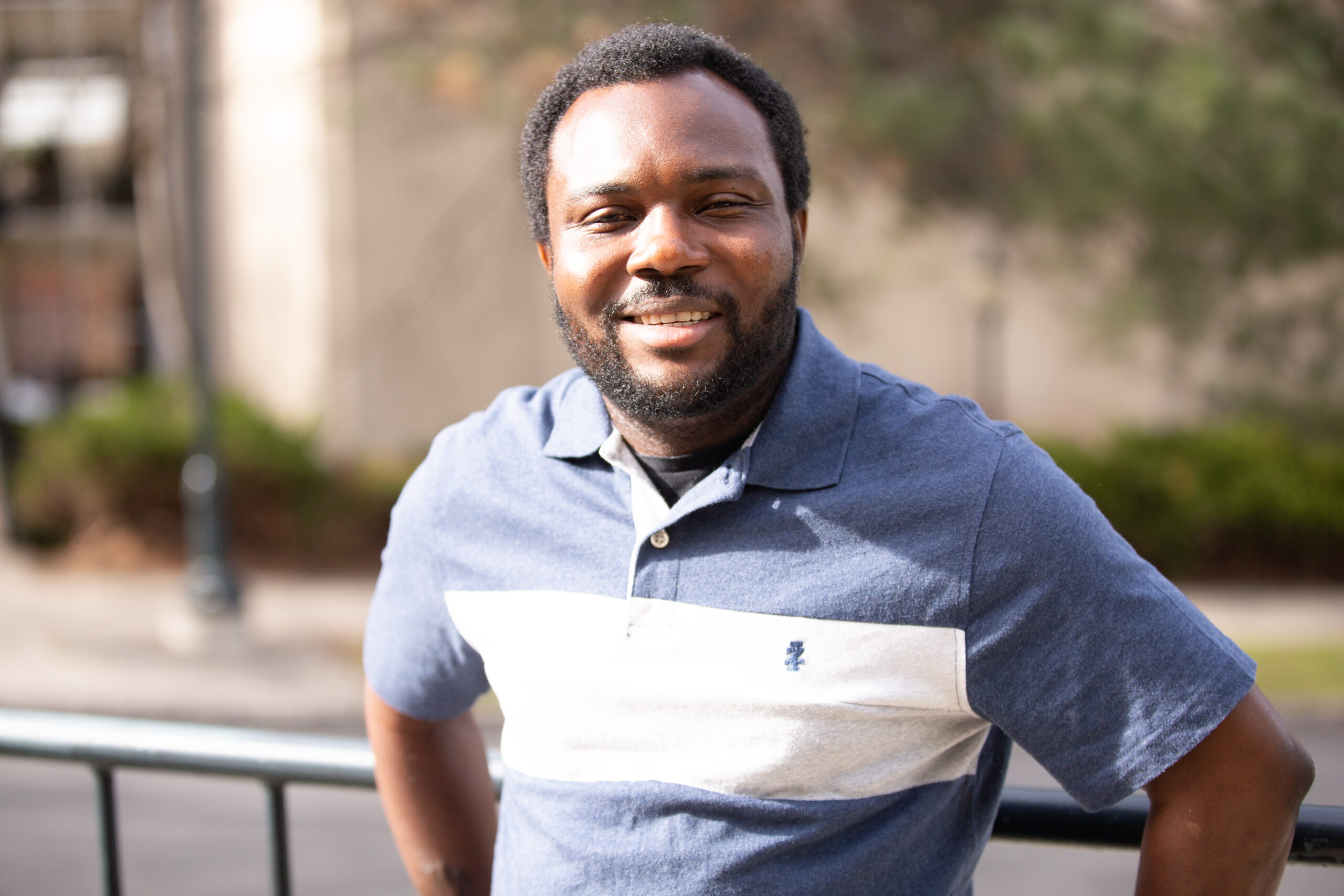 A portrait of Olasunkanmi Kehinde standing outside.