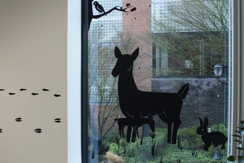 Black 2D artwork on walls and windows in library