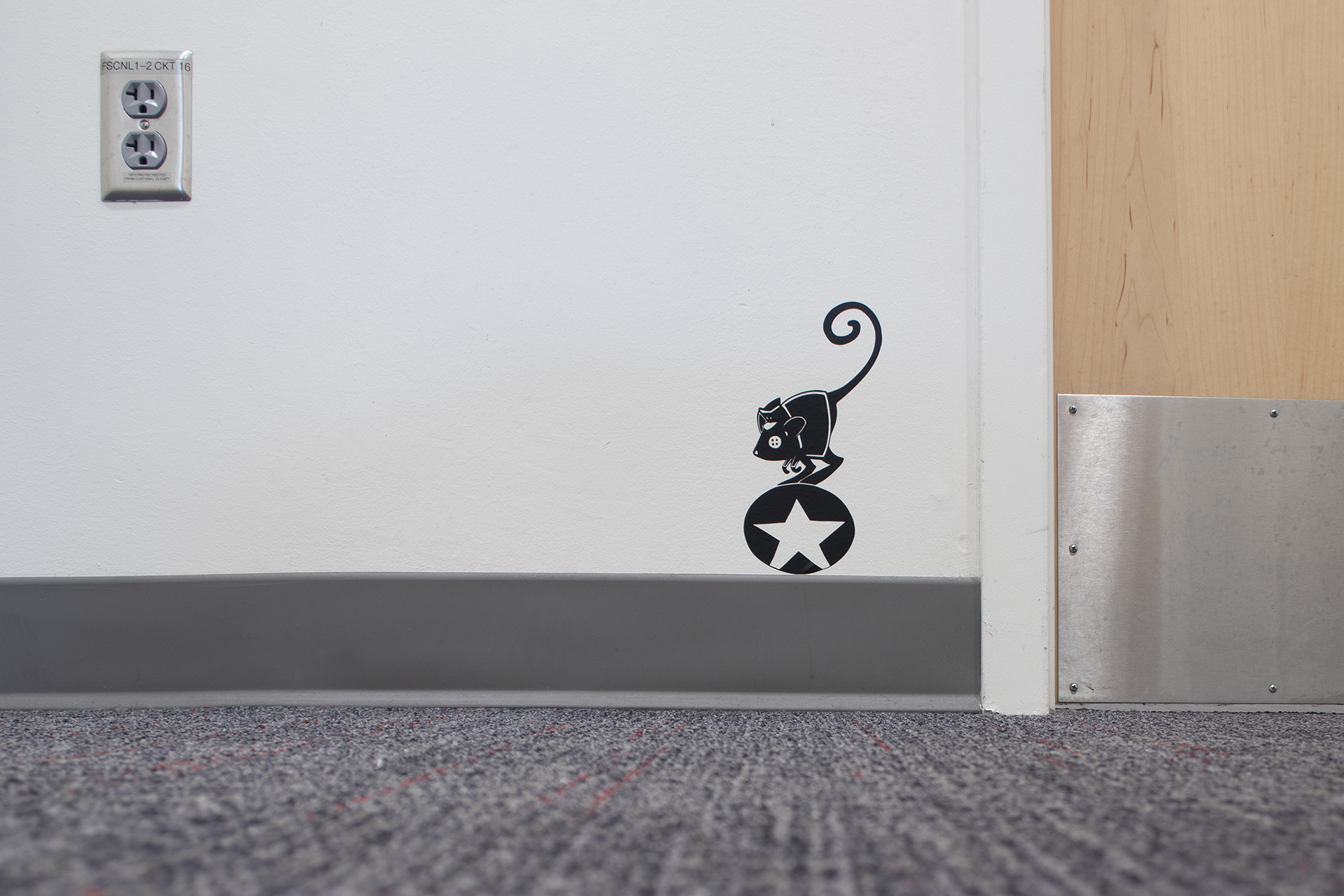 Black 2D artwork on book shelving in library (detail)