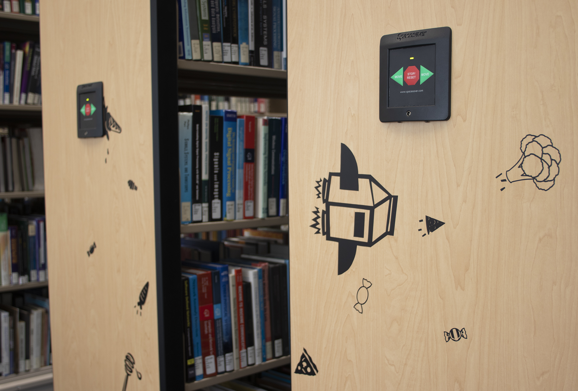 Black 2D artwork on book shelving in library (detail)