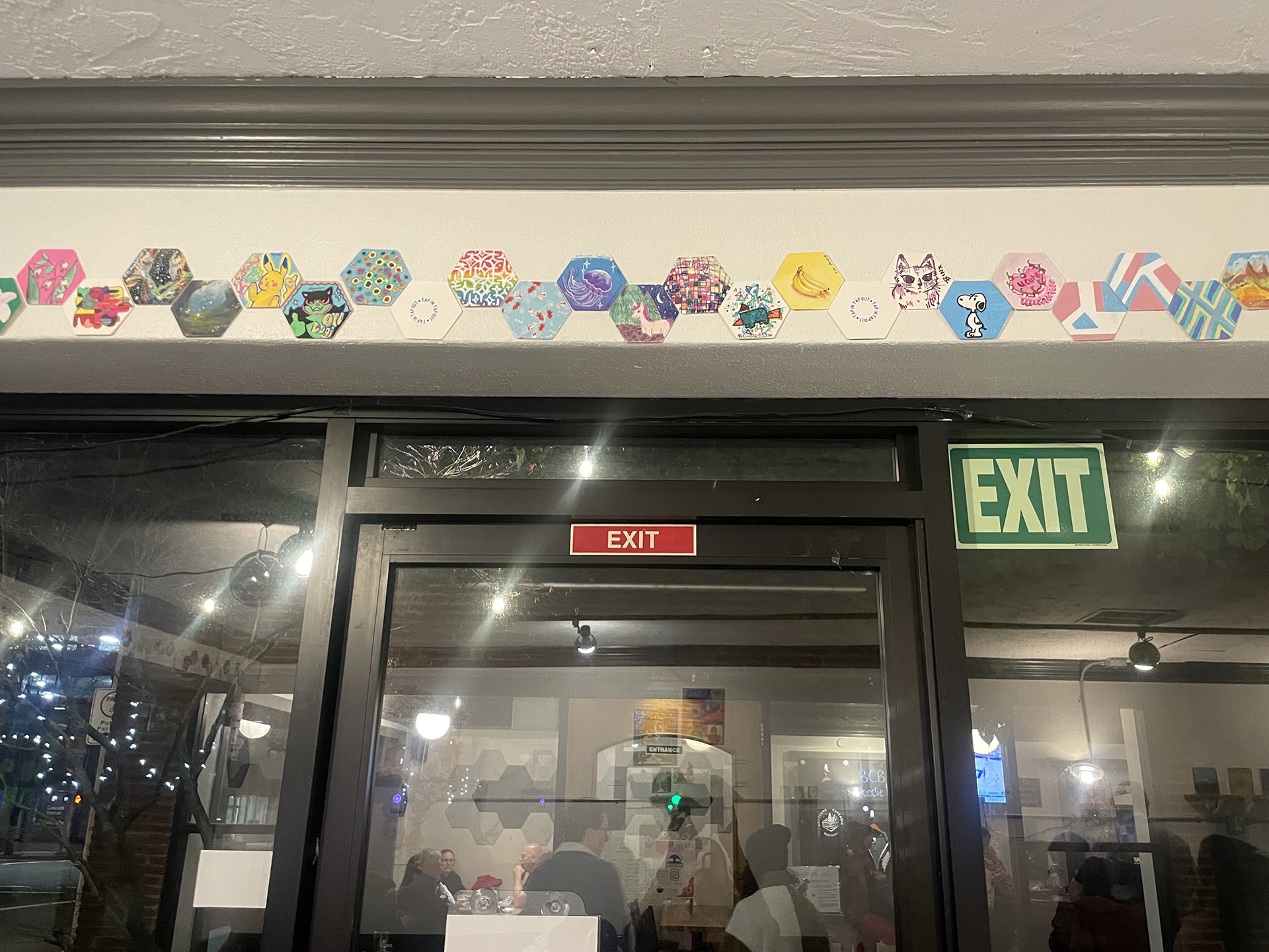 A sequence of hand drawn coasters on the wall from the opening.