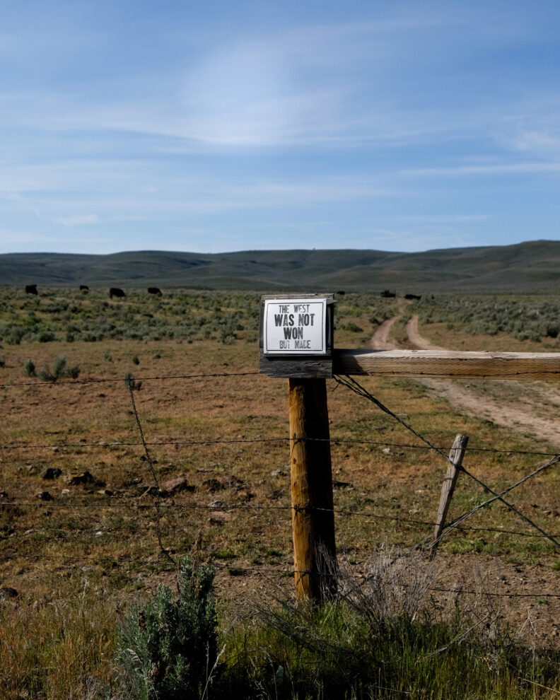 Photograph of one of Hannah's printson a fence that says the The West Was Not Won but Made.