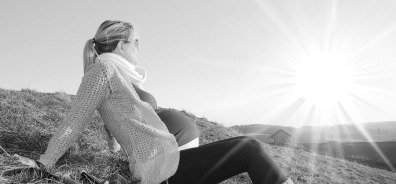 woman sitting on hill looking out at landscape