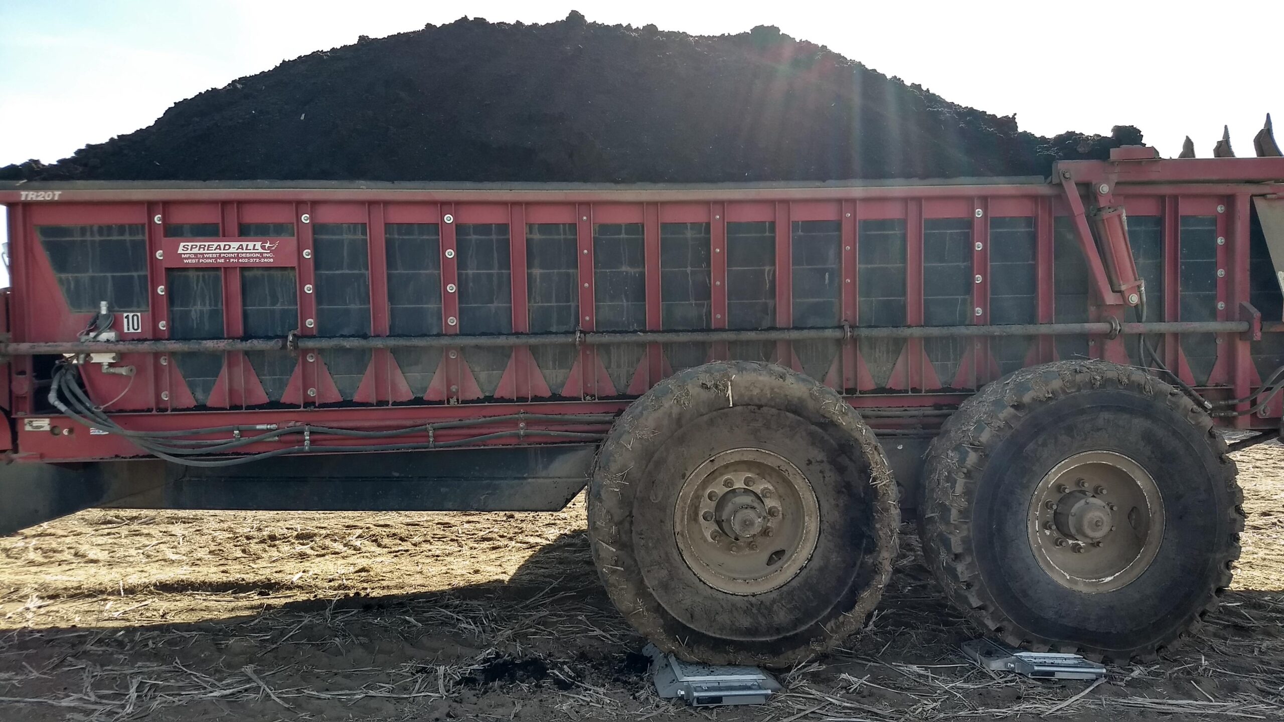 A biosolids spreader loaded to capacity on truck scales.