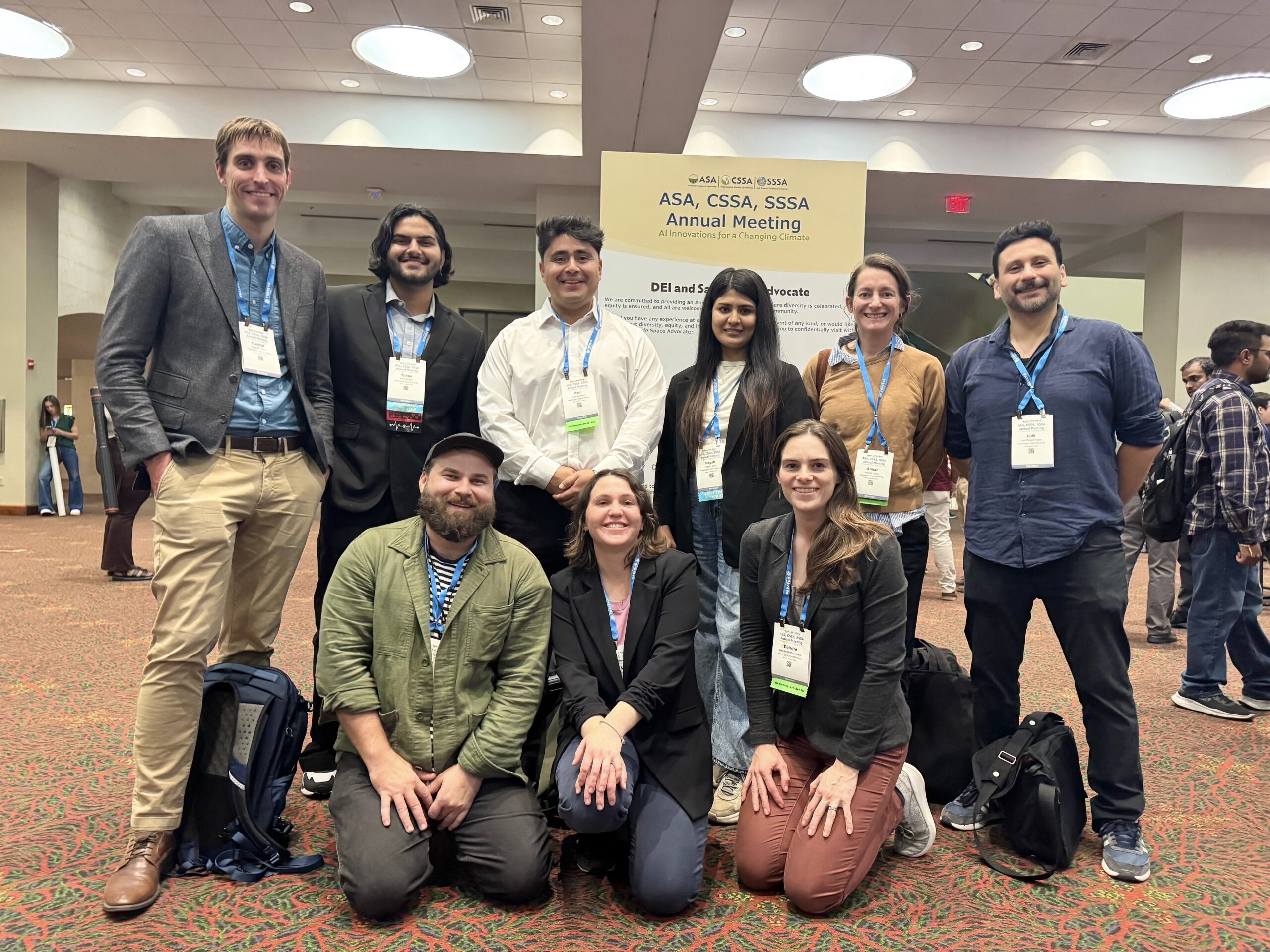 Research group smiling together in conference lobby.
