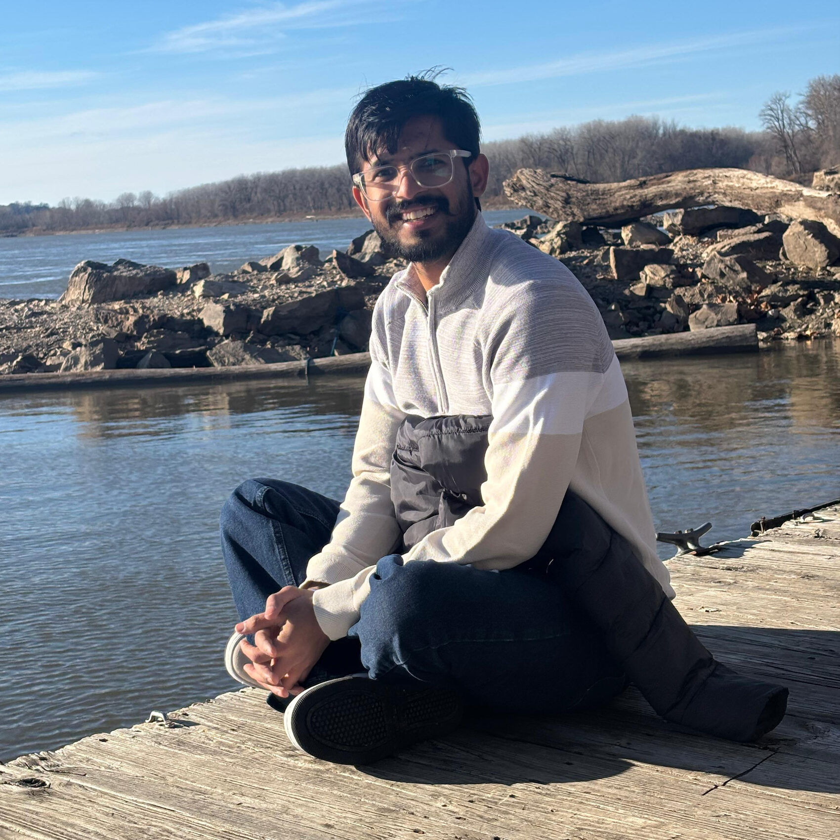 Charchit Bansal sitting on a dock with water in the background
