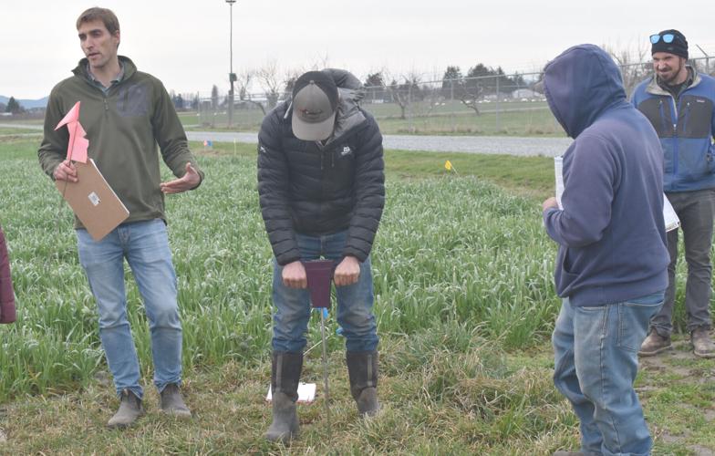 Four people. One man talking, another person using a soil probe.