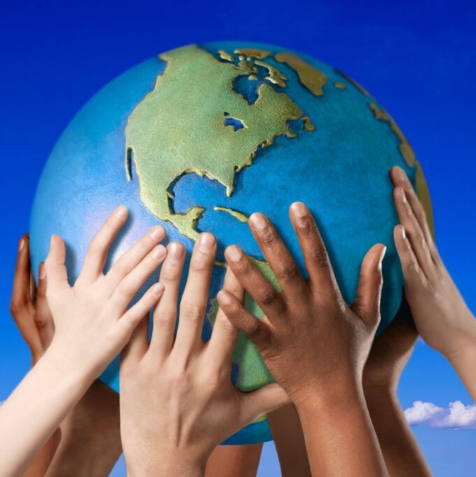 Multiple hands reaching up to hold a globe of Earth.