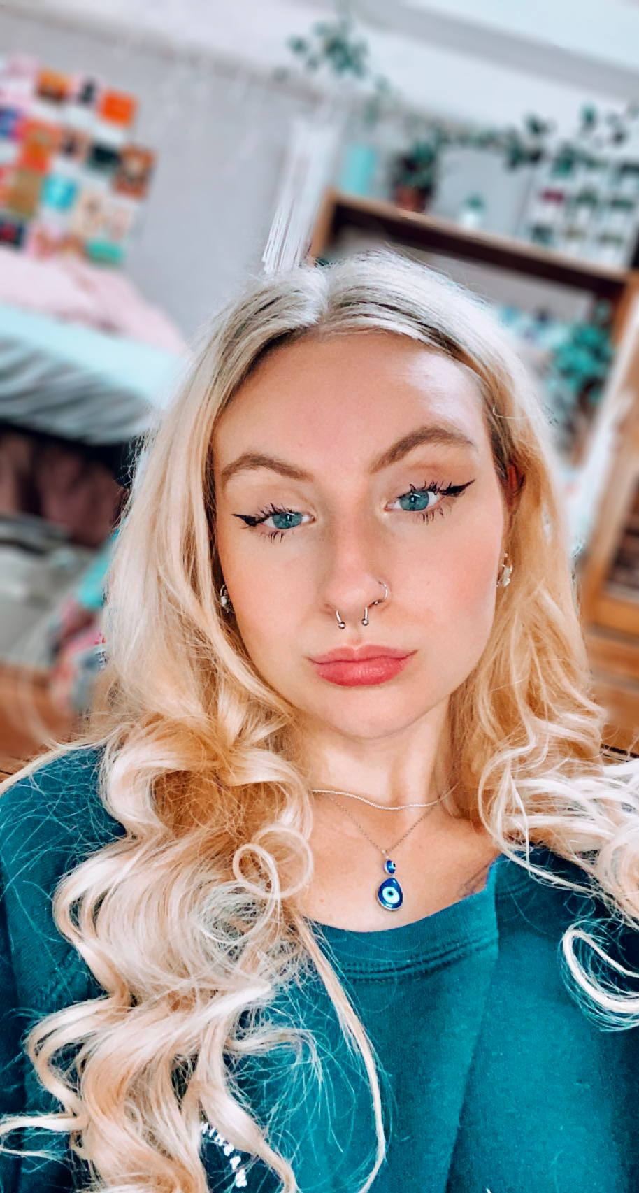 A woman with blond hair and a turquoise shirt smiling.