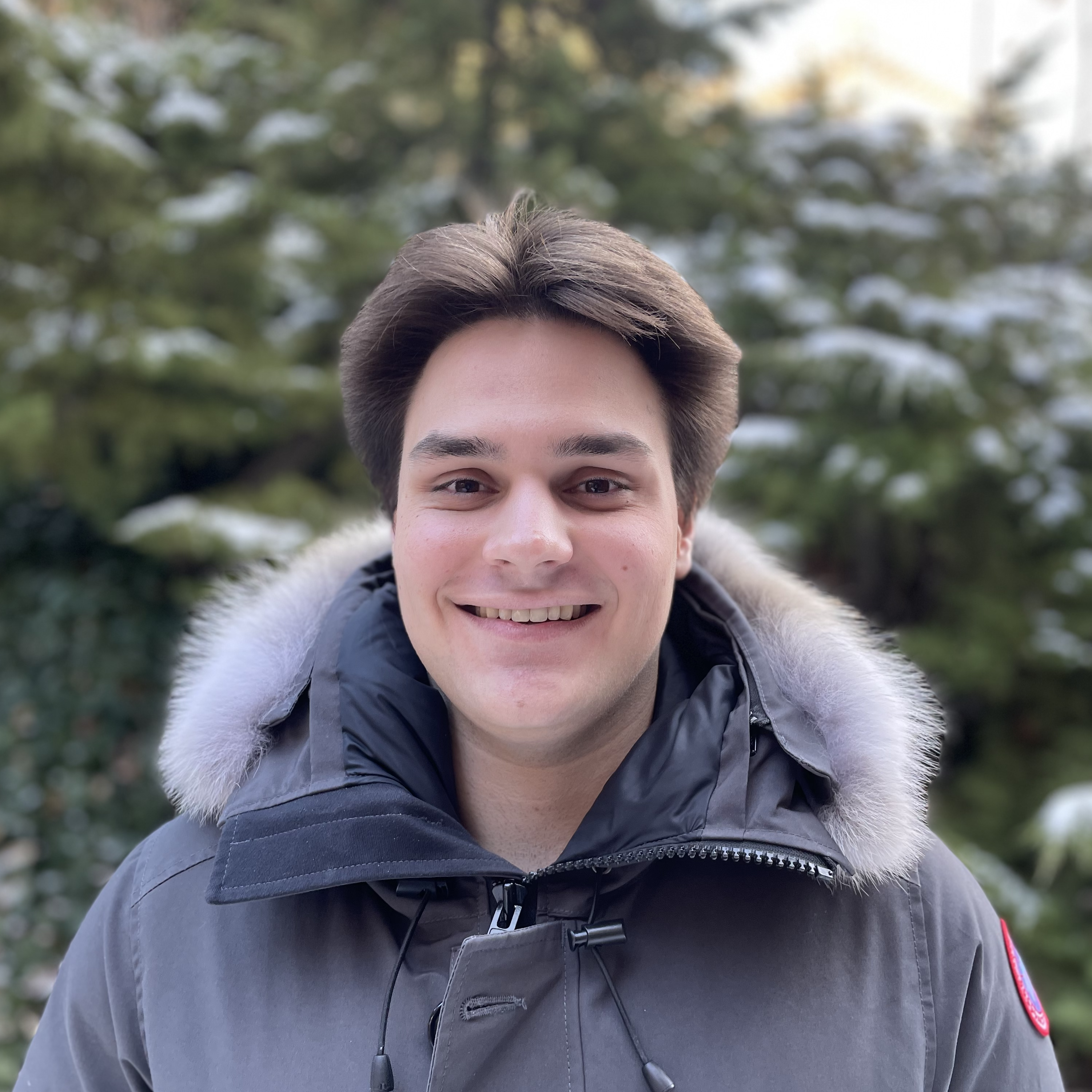 A man with brown hair wearing a winter coat smiling.