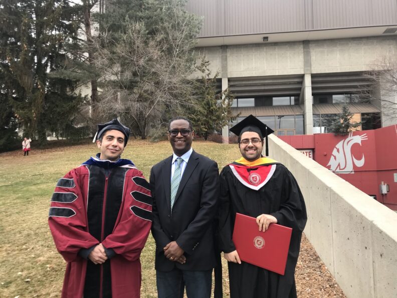Assefaw standing with two recently graduated students.