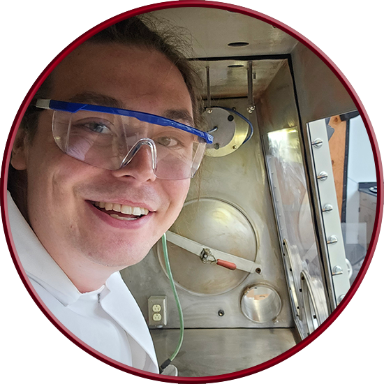 Picture of Christian taking a selfie from inside a decontaminated glove box with the front panels removed.