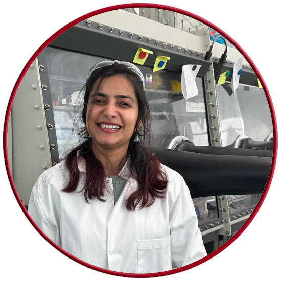 Picture of Palak smiling in the lab in front of the glove box. 