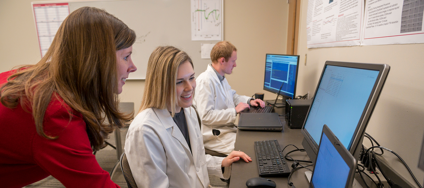 Faculty and student looking at computer analyzing research results