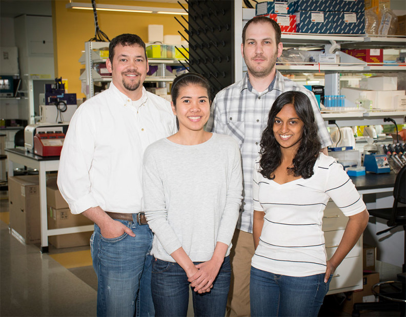 Christopher Davis and three researchers standing and smiling in the lab.
