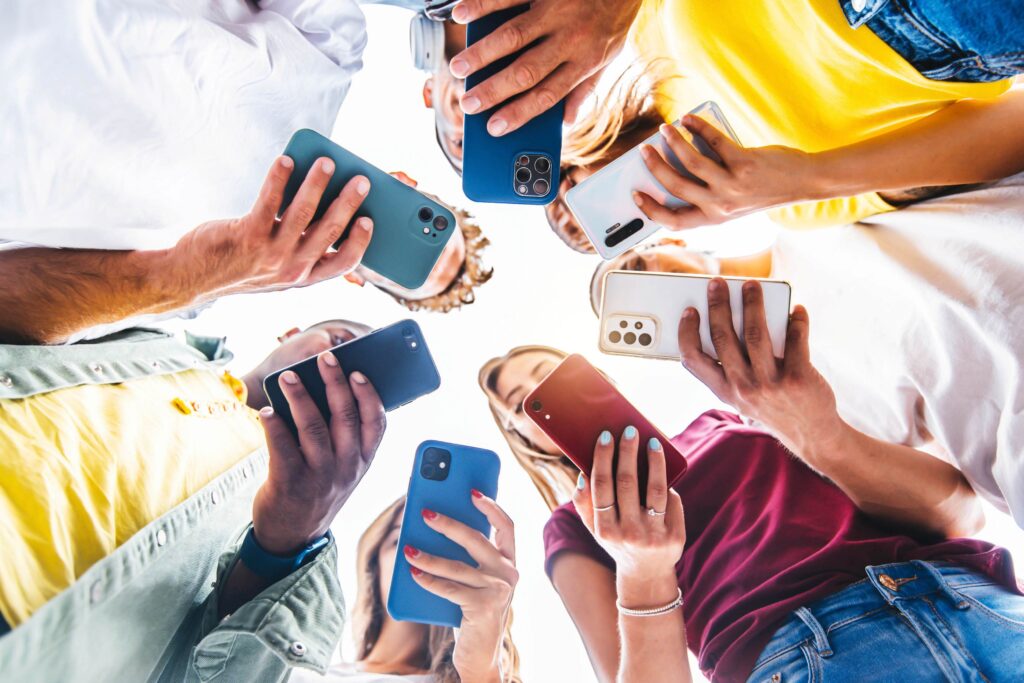 Five young adults holding phones and looking at screens