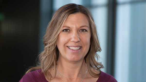 Dr. Shane Hentges in front of large windows. This photo shows her head and shoulders.