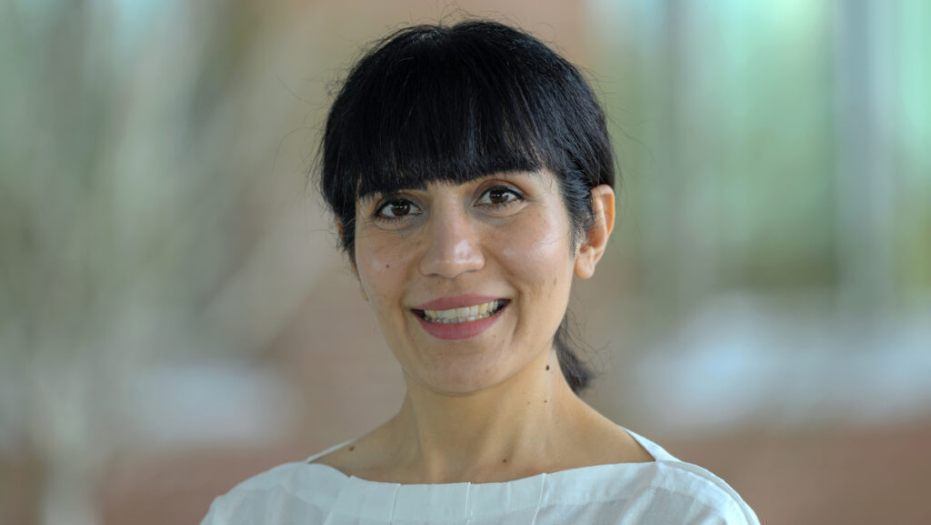 Shaghayegh outside. The background is completely blurred. Her hair is pulled back in a ponytail.